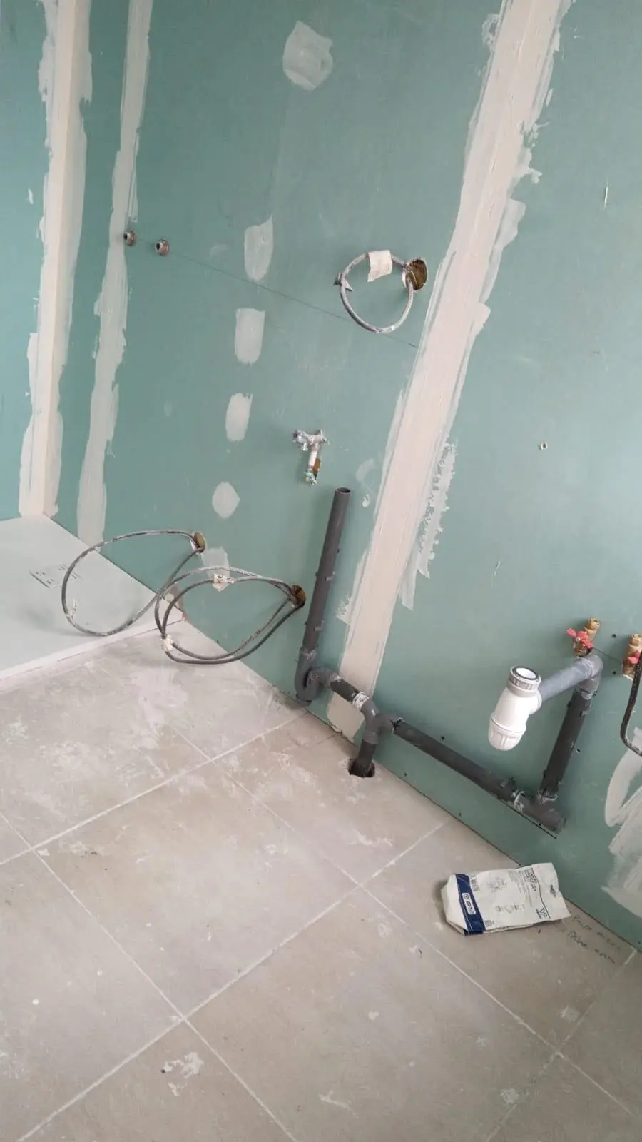Local professionnel en travaux avec chauffe-eau et sanitaires en cours d'installation